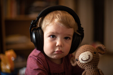 Niño rubio con su oso escuchando música con auriculares