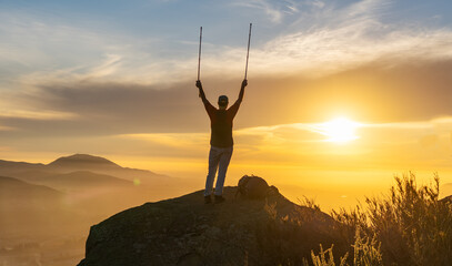 silhouette of a person on the mountains celebrating lifting trekking poles