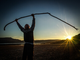 persona sujetando un palo a contraluz de un atardecer