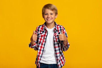 Cheerful young teen boy student show thumbs up sign recommends something for school