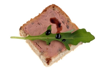 Amuse-bouche au foie gras avec une feuille de roquette et du vinaigre balsamique en gros plan sur fond blanc