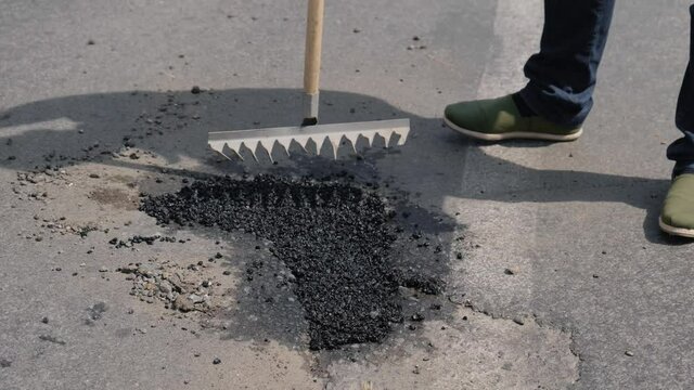 Ramming of asphalt with a rake. Close up the pit with soil in the city. Close-up on the road.