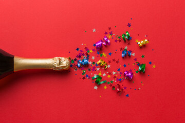 Creative flat lay composition with bottle of champagne and space for text on color background. Champagne bottle with colorful party streamers. holiday or christmas concept