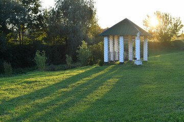 Pavilion with columns in the park at sunset.