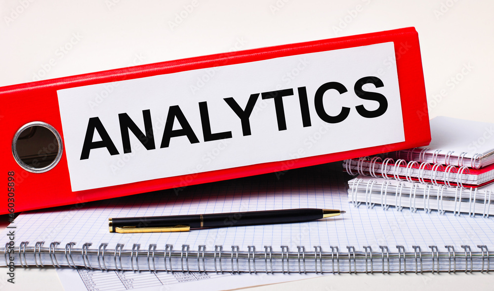 Fototapete On the desktop are notebooks, a pen and a red folder for papers with the text ANALYTICS. Business concept