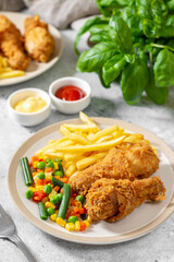 Fried crispy chicken legs in breadcrumbs in a white plate on a light culinary background. Fast food from the drumstick