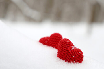 Valentines hearts in winter forest. Two red knitted hearts on snow, symbol of romantic love, background for holiday
