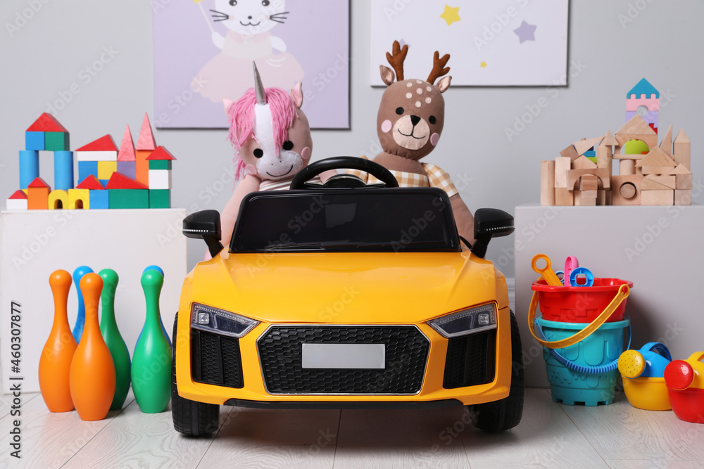 Wall mural Child's electric car with other toys near light wall in play room