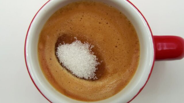 macro.Close up of a teaspoon of sugar that dips gently into a cup of italian coffee.breakfast.coffee break.creamy coffee