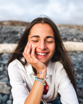 Smiling teen touching cheek on pebble shore