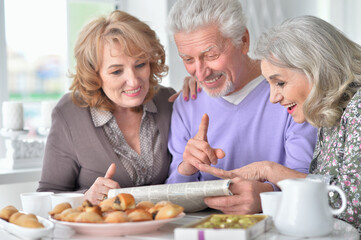 Senior people drinking tea and reading newspaper