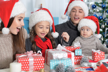 Obraz na płótnie Canvas Happy family in Santa hats preparing for Christmas