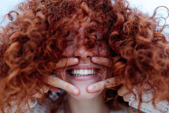 Cheerful ginger woman showing victory gesture