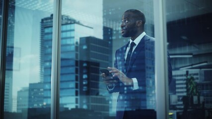 Portrait of Successful Black Businessman Wearing Suit Standing, Using Smartphone Looking out of the Window. Successful African CEO Planning e-Commerce Investment Strategy. From Outside Shot - Powered by Adobe