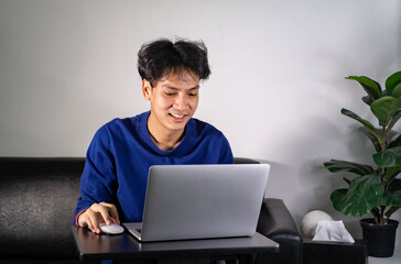 young man using laptop computer, typing on keyboard, writing email or message, chatting, shopping, lerning, successful freelancer working online on computer, sitting in modern living room at home.