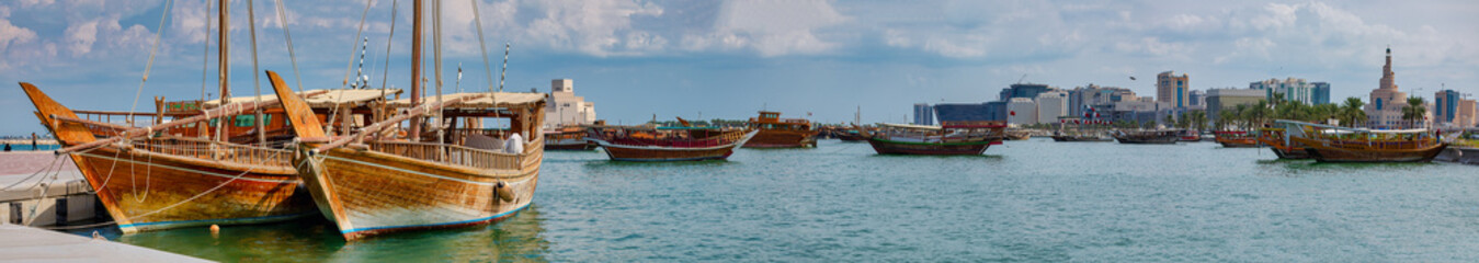 Traditional Arabic Dhow boats in Doha harbor during blue sunset, Qatar.