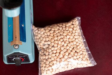 Bag of chickpeas sealed next to the sealer. Plastic film sealer. Concept of urban, manual and simple works.