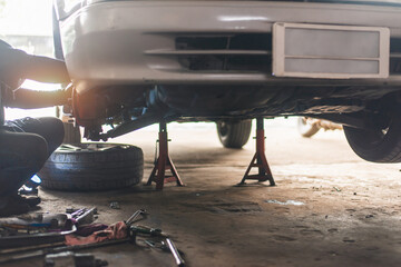 Fototapeta premium Male mechanic repairing suspension system of car in garage