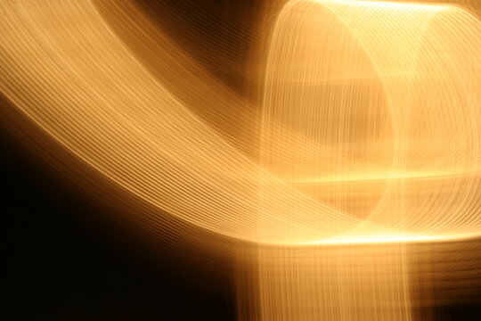 Luz hal&oacute;gena de color amarillo anaranjado en movimiento y velocidad formando un dise&ntilde;o abstracto con desenfoque en el espacio con fondo oscuro.