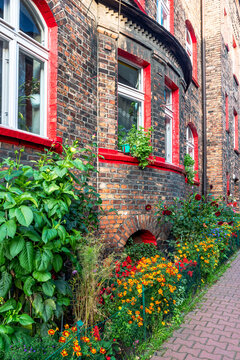 Facade of an old, traditional, silesian brick block house in Nikiszowiec, Katowice, Poland. Small, colorful garden in front of the building.