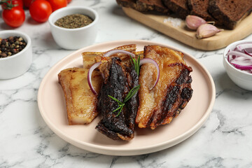 Tasty fried pork lard with rosemary and onion on white marble table