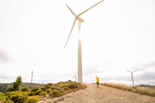 A man stands near the wind turbines