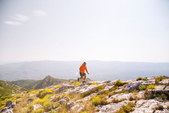 Male hiker running on rocks in mountain - Powered by Adobe