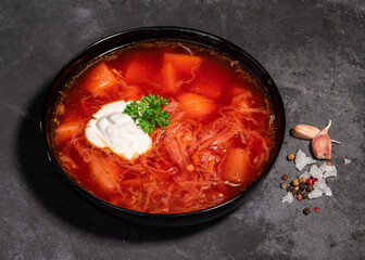 Borsch. Ukrainian soup. Red soup. Borsch with sour cream and onions, white bread. Traditional Russian borsch with sour cream. The concept of delicious food with sour cream on a black background