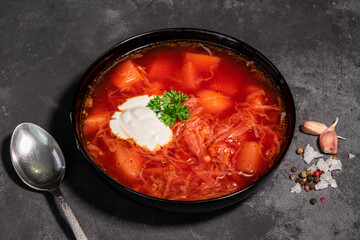 Borsch. Ukrainian soup. Red soup. Borsch with sour cream and onions, white bread. Traditional Russian borsch with sour cream. The concept of delicious food with sour cream on a black background