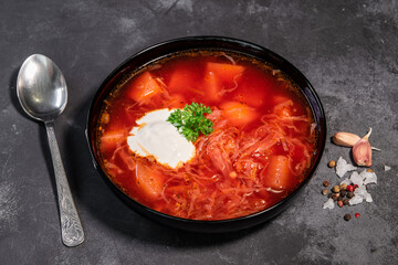Borsch. Ukrainian soup. Red soup. Borsch with sour cream and onions, white bread. Traditional Russian borsch with sour cream. The concept of delicious food with sour cream on a black background