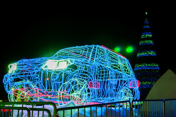 New Year's car made of glowing diode led bulbs near the Christmas tree in the night city