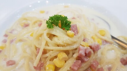 Spaghetti white sauce put ham and corn in a white dish