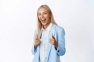 Successful businesswoman winking and smiling, pointing fingers at camera to praise, compliment you,...