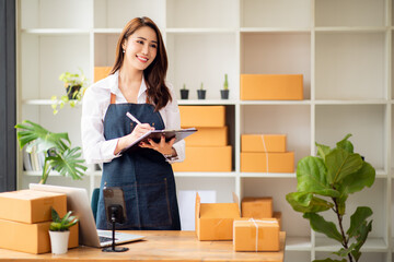 Starting Small business entrepreneur SME freelance, Portrait young woman working at home office, BOX, smartphone, laptop, online, marketing, packaging, delivery, b2b, SME, e-commerce concept.