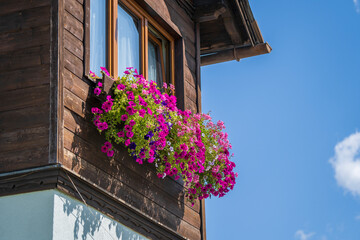 Fototapeta na wymiar The wooden mezzanine of an old farm mountain house with colorfull flowers in Austria