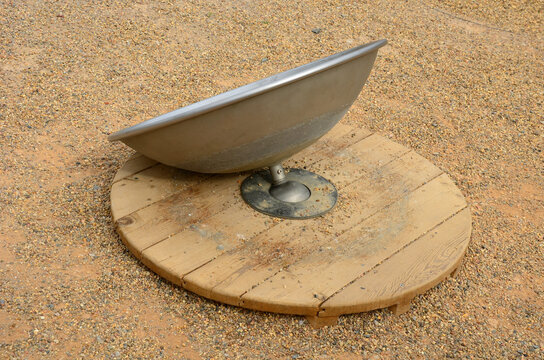 play element in the park on a children's playground in the shape of a parabola anchored to a round wooden base. Balance training using a ball joint in the middle of the outside. stainless steel bowl