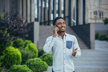 Young male businessman, cheerful talking on a mobile phone in casual clothes, freelancer worker happily communicates with colleagues