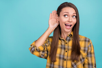Portrait of positive cheerful person arm palm near ear look empty space isolated on blue color...