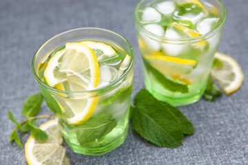 Two glasses of fresh lemonade drink or mojito cocktail on gray	 backdrop
