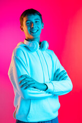 Portrait of young man, student or boy in casual clothes smiling isolated on magenta studio backgroud in neon. Human emotions concept.