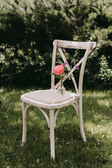Rustic wooden chair with red flower on the top.