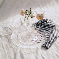 Fototapeta na wymiar Close-up of decorative concept for celebration table with glass tableware and blue checkered handkerchief on a white background