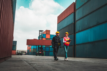 Industrial worker works with co-worker at overseas shipping container yard . Logistics supply chain management and international goods export concept . - obrazy, fototapety, plakaty