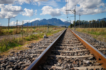 Wide angle of railroad in countryside setting with mountain background.