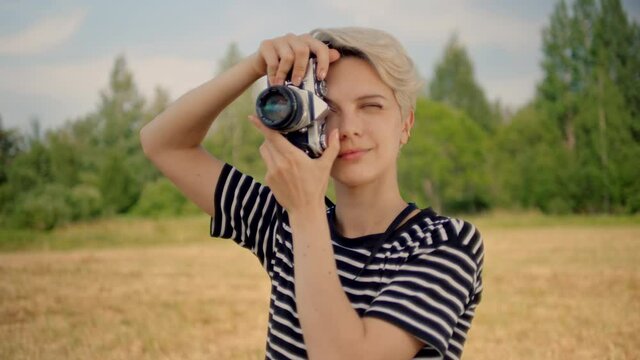 Professional female photographer gives directions to model behind lens. Happy occupation empowered and independent woman work for commercial magazine or agency.Young woman make photos on analog camera