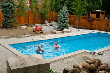 Two women swimming in newly installed pool with back yard landscaping construction Barrie Ontario Canada