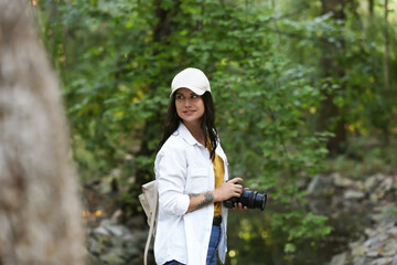 Beautiful woman with camera spending time in nature reserve