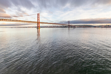 the 25 de Abril suspension bridge over Tagus river in Lisbon, Portugal at sunrise