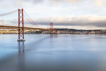 the 25 de Abril suspension bridge over Tagus river in Lisbon, Portugal at sunrise