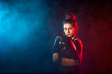 Fototapeta na wymiar Young woman doing boxing training at the gym, she is wearing boxing gloves